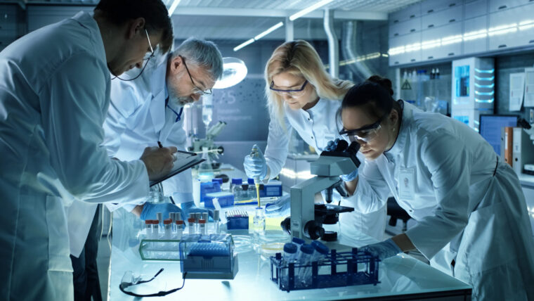 A team of laboratory technicians work in a lean lab. Perhaps they are discussing tactics for increasing efficiency in QC labs?