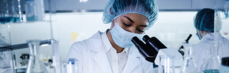 Scientists examines DNA models in modern Genetic Research Laboratory. Computer monitors with data in foreground