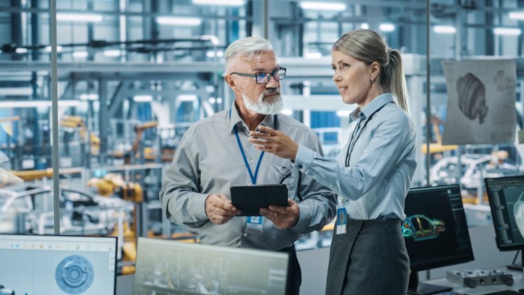 Car Factory: Female Project Manager Talks to Male Automotive Engineer, Plan Strategy Using Tablet Computer. Automated Robot Arm Assembly Line Production Conveyor Manufacturing Electric Vehicles