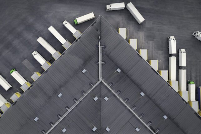 Aerial view of a large distribution warehouse with loading docks and many trucks.