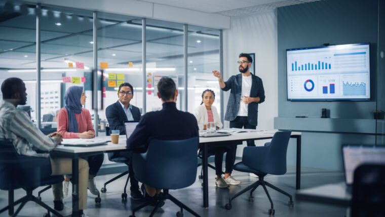 Businessman Leads Business Meeting with Managers, Talks, uses Presentation TV with Statistics, Infographics.