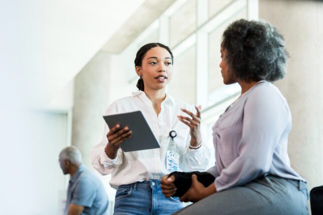 Therapist gestures while asking woman questions about injury