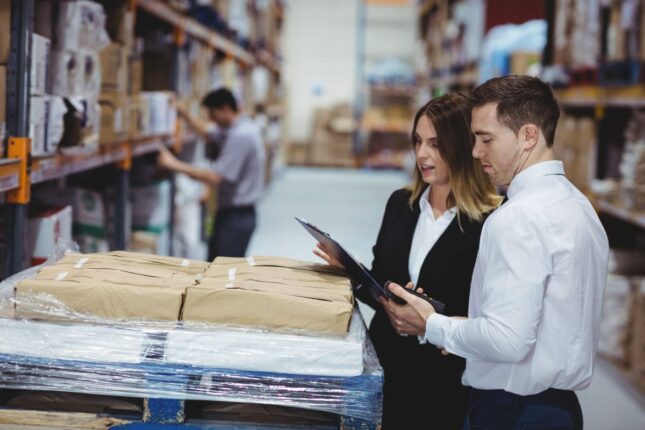 Warehouse managers looking at clipboard in warehouse