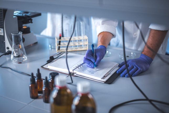 A lab scientist wearing nitrile gloves writing in a notebook. Maybe their notes will reveal what makes a great lab planner?