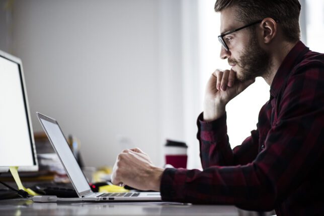 Young man thinking and working in the office, maybe contemplating the best lab scheduling solution for his laboratory