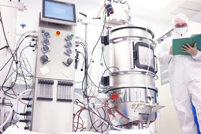 Scientist in a clean room laboratory reviewing documentation for a bioreactor, representing our autologous therapy slot allocation case study