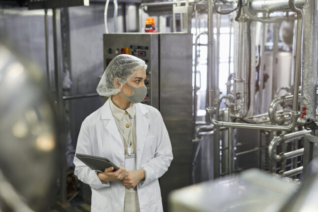 A scientist with a clipboard monitors quality on a real time release production line