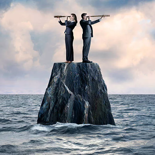 A businessman and a businesswoman are stranded atop a lonely rock in the middle of the ocean looking through a spyglass. They stand back to back as they peer in opposite directions as they work together to seek a solution.