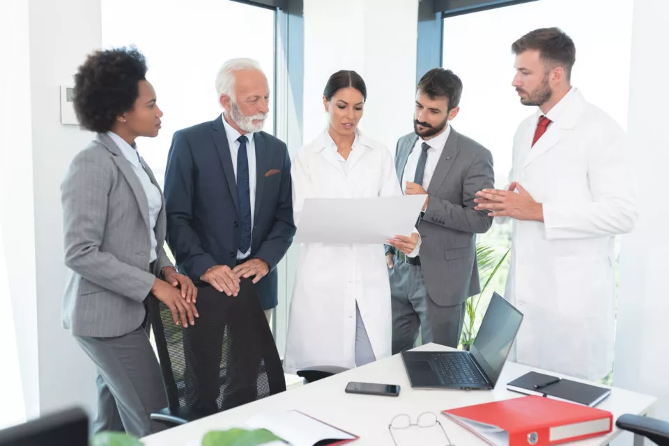 Business people with medical workers analyzing document at office