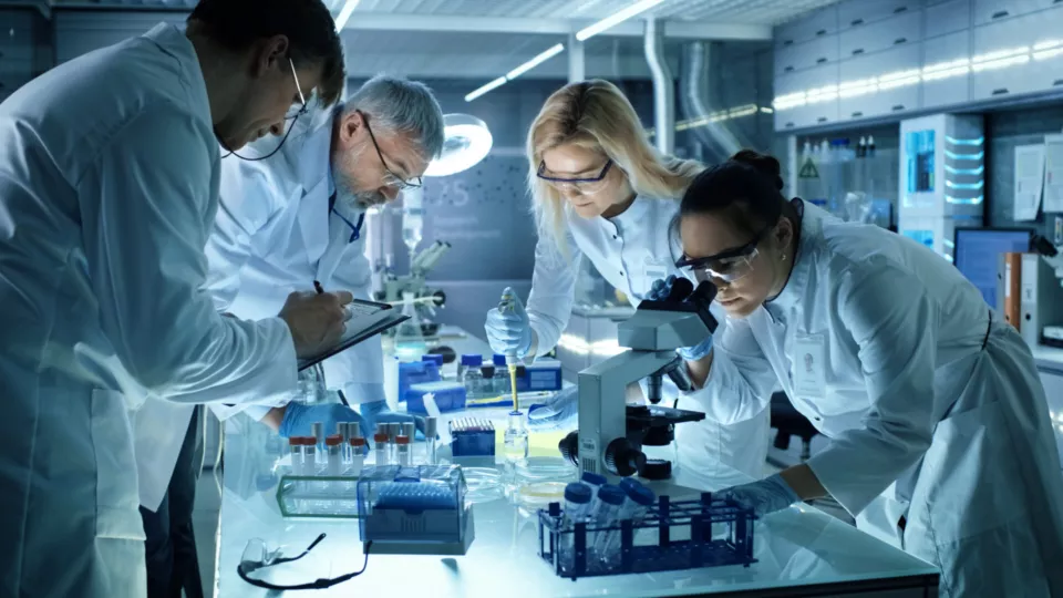 Team of Medical Research Scientists Collectively Working on a New Generation Experimental Drug Treatment. Laboratory Looks Busy, Bright and Modern.