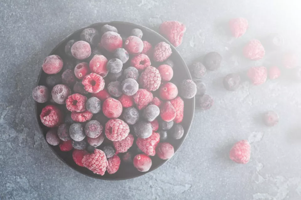 Frozen raspberry, blueberry, cranberry on black background. Frozen fruit. Top view, flat lay, close up.